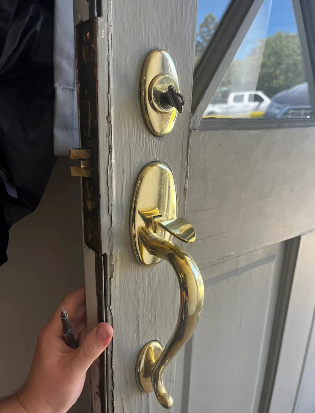 Polished brass handleset and deadbolt on a painted wood door with the lock edge exposed