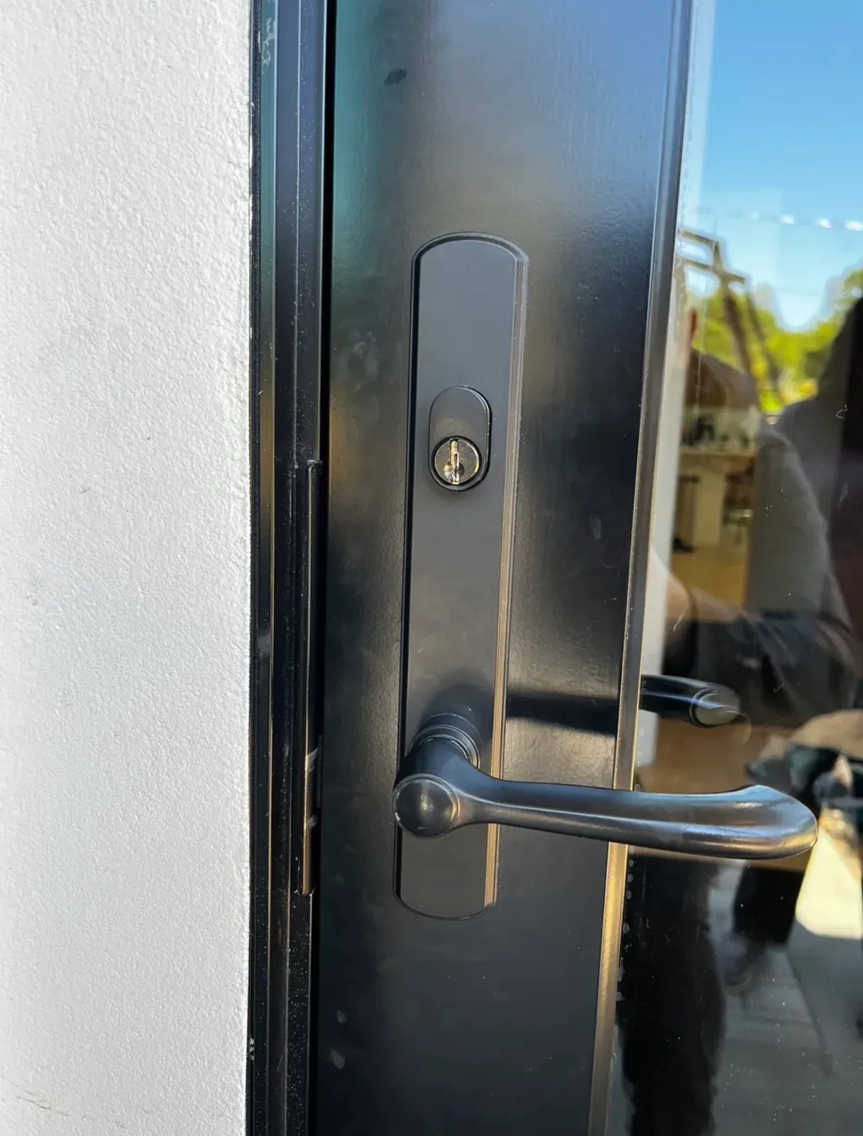Black lever handleset with a keyed cylinder on a glass entry door