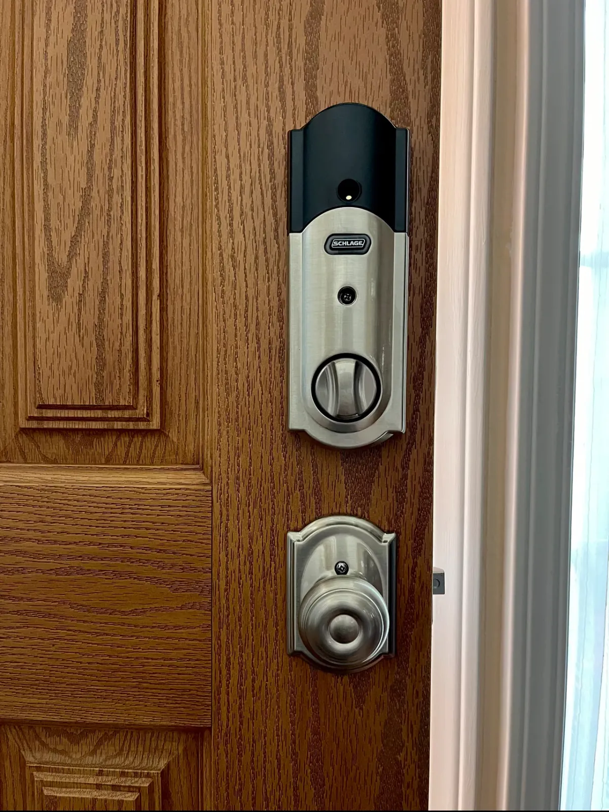 Schlage smart deadbolt with a matching satin-nickel knob on a wood-grain front door